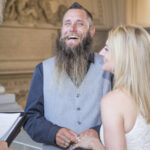 A photo of a Smiling Groom putting a wedding ring on the bride in San Francisco City Hall