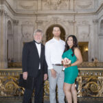 A photo of The officiant with the couple on the Mayor's Balcony