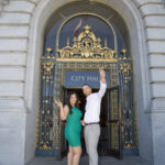 A photo of a newly married couple celebrating at the entrance to City Hall