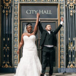 A photo of a couple celebrating their marriage at the entrance to SF City Hall