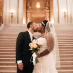 A photo of a couple enjoying a kiss on the grand staircase in San Francisco City Hall