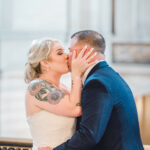 A photo of a couple enjoying their First Kiss on the Mayor's Balcony in San Francisco City Hall