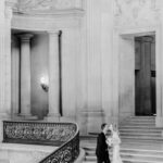 A photo of a couple exchanging a Kiss on the Grand Staircase in San Francisco City Hall